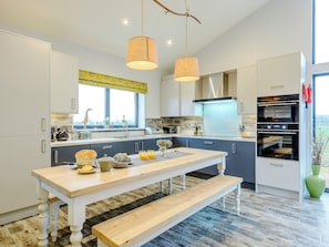 Une cuisine moderne avec des armoires blanches, une table en bois et un four encastré.