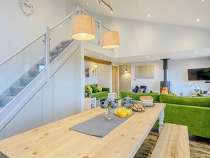 A modern living room with a staircase, a fireplace, and a dining area with a table set for breakfast.