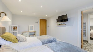 A bedroom with two beds, a TV mounted on the wall, a wardrobe, and a mirror.
