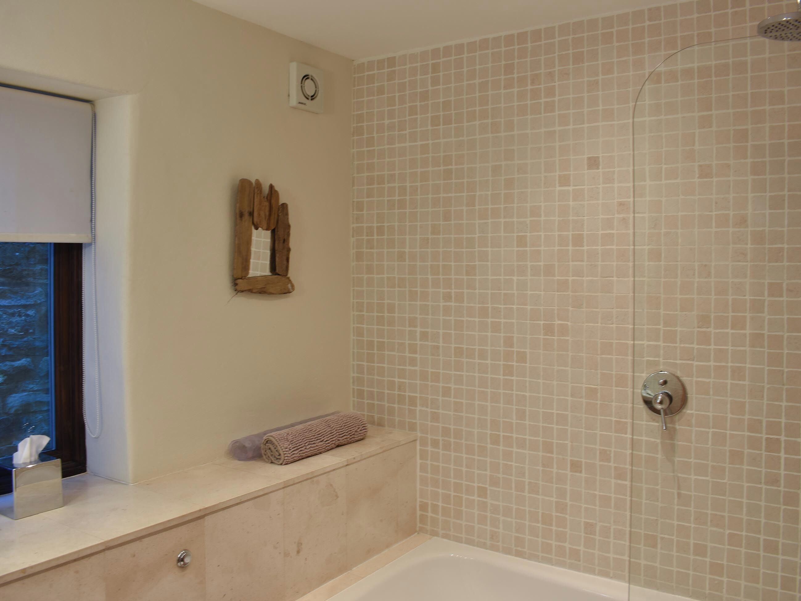 Un baño con bañera, ducha, toalla y espejo en la pared.