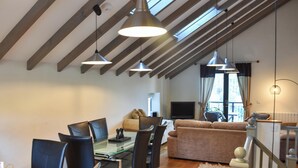 Un coin repas avec une table et des chaises en verre, un canapé et un téléviseur dans le salon.