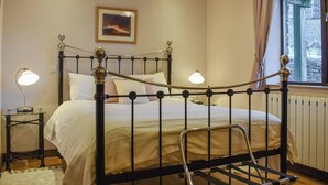 Une chambre à coucher avec un lit en métal, des lampes de chevet, un tableau encadré au mur et une fenêtre avec des rideaux.
