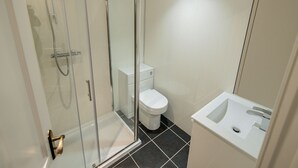 Une salle de bain moderne avec une douche à parois de verre, des toilettes blanches et un lavabo avec un miroir.