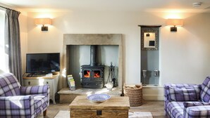 A cozy living room with a fireplace, plaid furniture, and a television. - Mill House Cottage - UK1475 (Middleton, near Kirkby Lonsdale)