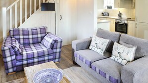 A living room with two sofas, one plaid and one grey, a coffee table, and a staircase. - Mill House Cottage - UK1475 (Middleton, near Kirkby Lonsdale)