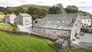 A stone building with a gravel driveway, surrounded by green fields and trees. - Mill House Cottage - UK1475 (Middleton, near Kirkby Lonsdale)