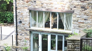 A stone building with a two-story window, a door, and a small balcony. - A charming two bedroom cottage, located in the village of Alston. (Alston)