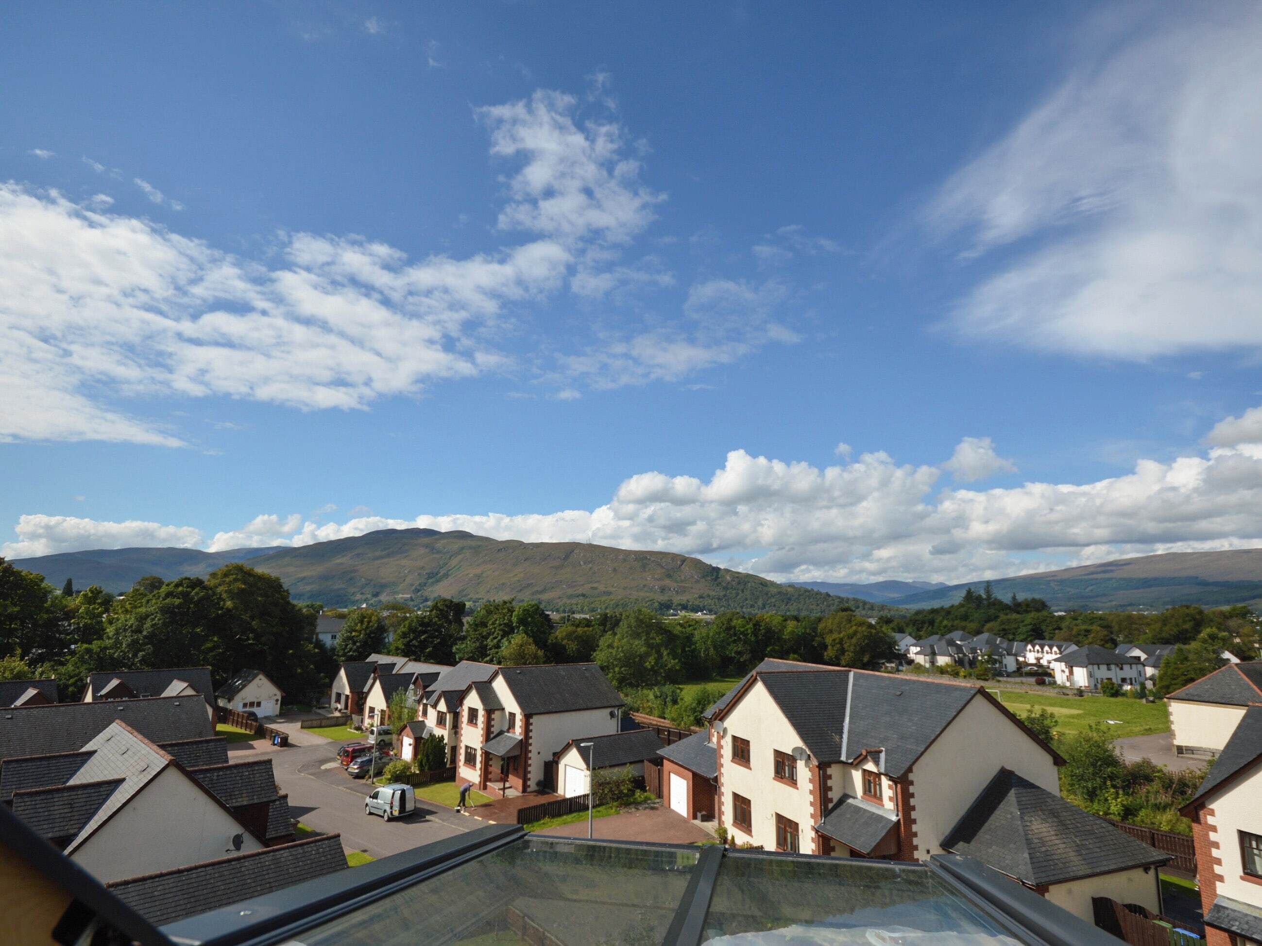 A residential area with houses, a clear sky, and distant mountains.