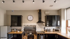 Una cucina moderna con pensili neri, una cappa in acciaio inossidabile, un camino a legna, un forno a microonde e una sveglia appesa al muro.