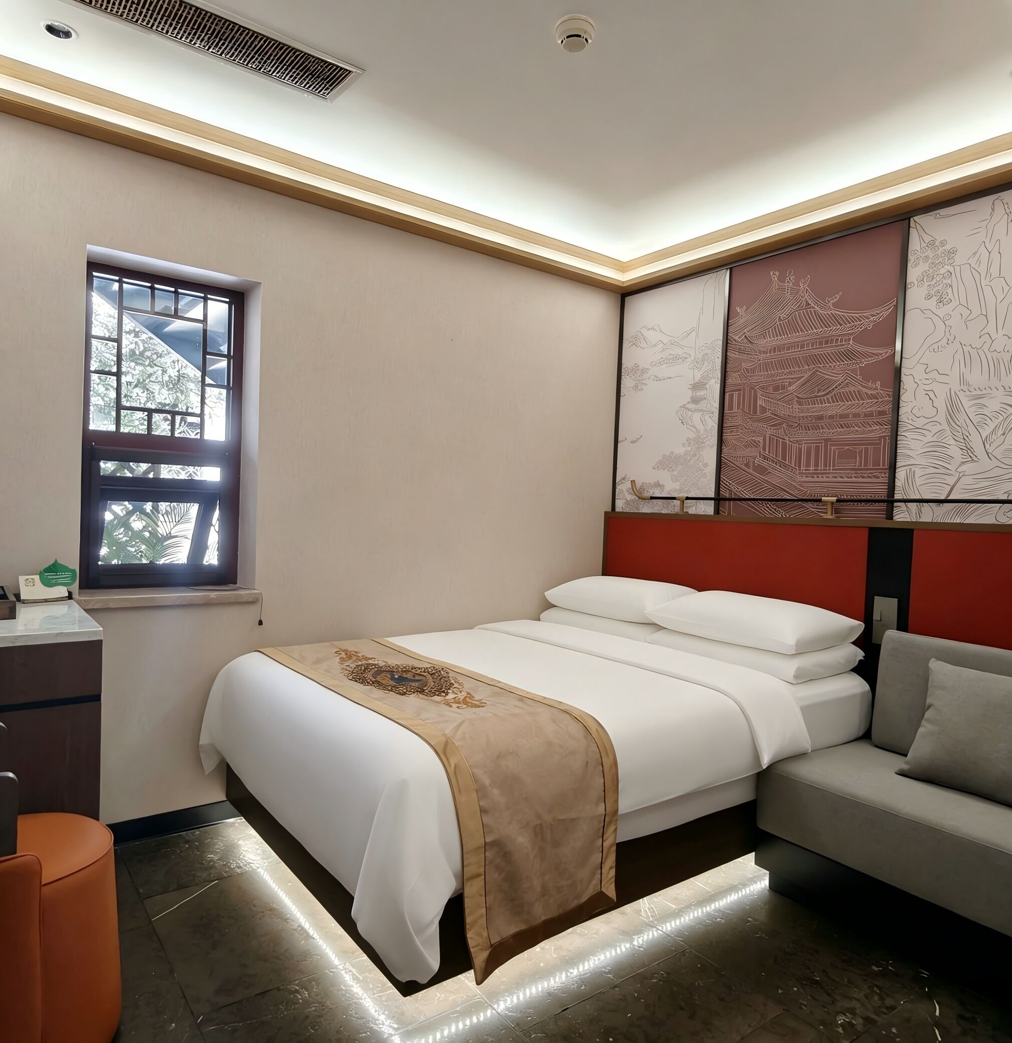 Une chambre d’hôtel avec un lit, une fenêtre, un bureau et un mur d’accent de couleur rouge.