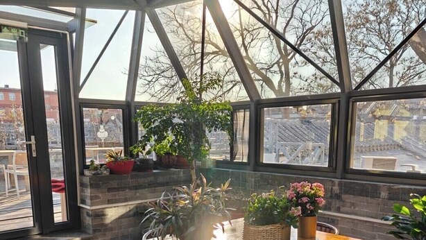 A dining area with a wooden table and chairs, surrounded by large windows with a view of the cityscape. - Youfang Hotel - Beijing Tian'anmen Wangfujing Store (Beijing)