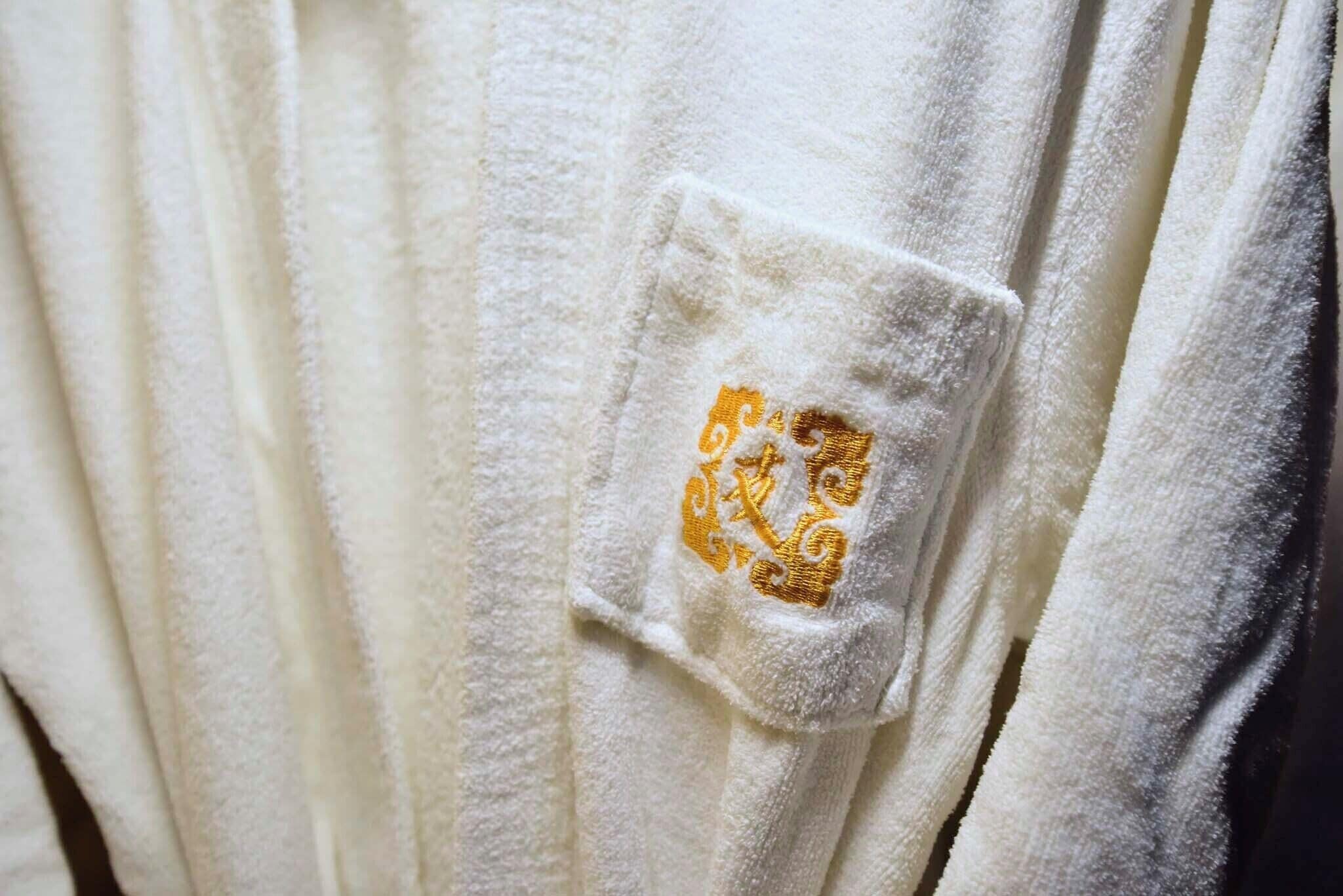 Una toalla blanca con un logotipo dorado bordado.