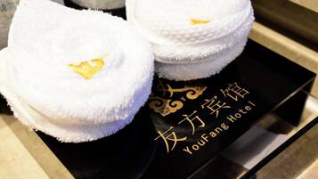 Two white towels with gold embroidery on a black tray with gold text.