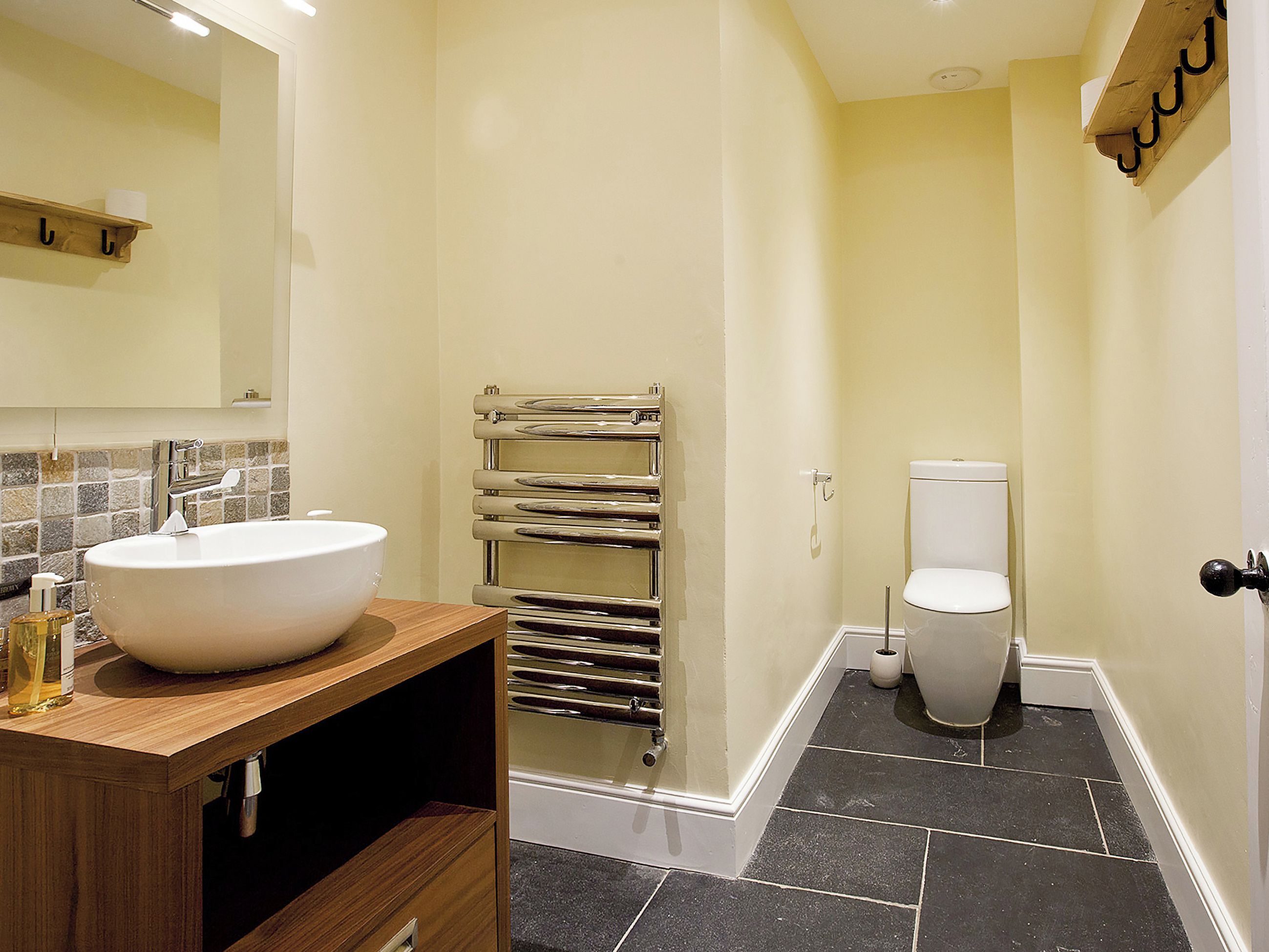A bathroom with a large white sink, a towel rack, a toilet, and a mirror.