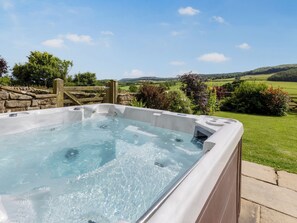 A hot tub with a stone wall and wooden gate, surrounded by greenery and a scenic countryside view. - Thirley Cotes Farmhouse (Harwood Dale, near Scarborough)