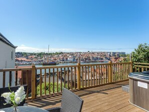 Une terrasse en bois offrant une vue sur un port et une ville.