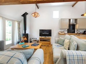 A cozy living room with a fireplace, a television, a sofa, and a kitchen area. - 2 bedroom accommodation in Harwood Dale, near Scarborough (Harwood Dale, near Scarborough)