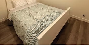 Quarto com cama, cabeceira de madeira e janela.
