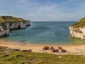 A coastal beach with cliffs, boats, and a tractor on the sand. - 3 bedroom accommodation in Harwood Dale, near Scarborough (Harwood Dale, near Scarborough)