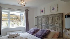 A bedroom with a bed, a chandelier, a window with curtains, and artwork on the wall. - 3 bedroom accommodation in Whitby (Whitby)