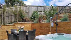 An outdoor patio with wicker furniture and a hot tub. - 3 bedroom accommodation in Whitby (Whitby)