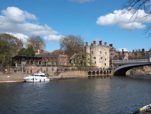 A historic building with a stone facade, a bridge, and a boat docked by the river. - 1 Monkbar Mews - UK2690 (York)