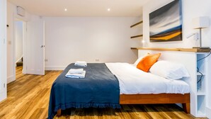 Quarto com cama, pintura e chão de madeira.