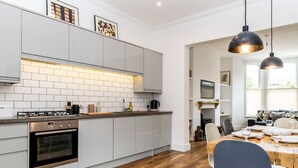 Cozinha moderna com armários brancos, bancada de madeira e área de refeições com mesa posta para dois.
