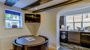 A modern kitchen with built-in appliances, a dining area with a round table, and a view of the outdoors. - 2 bedroom accommodation in Whitby (Whitby)