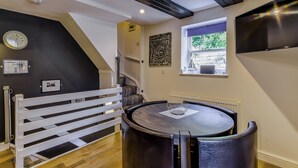 A room with a round table, a white bench, a window with a view, and a black ceiling. - 2 bedroom accommodation in Whitby (Whitby)