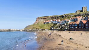 A coastal town with a prominent church on a hill, a sandy beach, and a rocky shoreline. - A historical cottage, tucked away in the heart of Whitby’s old town. (Whitby)