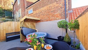 A patio with a table set for breakfast, including croissants and juice, and a small hot tub. - A historical cottage, tucked away in the heart of Whitby’s old town. (Whitby)