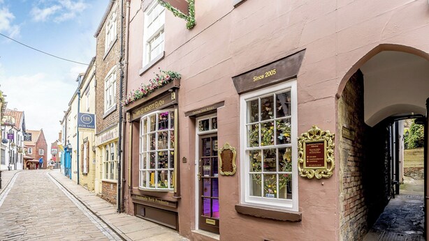 A historic street with cobblestone pavement, a shop with a 'Handmade Bath Products' sign, and a 'Since 2005' plaque. - A historical cottage, tucked away in the heart of Whitby’s old town. (Whitby)