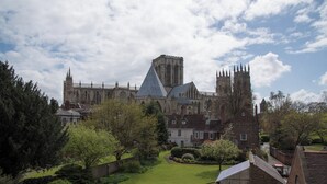 Un bâtiment historique doté d’une tour imposante et de flèches, entouré de jardins et de sentiers bien entretenus.