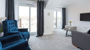 A modern living room with a blue armchair, a grey sofa, and a flat-screen TV on the wall. - 1 bedroom accommodation in York (York)