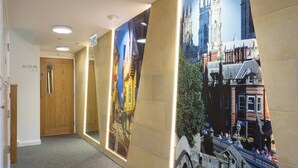 A hallway with a large poster of a historic building, a wooden door labeled "AURAM AF-P", and a carpeted floor. - 1 bedroom accommodation in York (York)