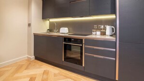 Una cocina moderna con armarios oscuros, un lavamanos de acero inoxidable, un tostador y una cafetera.
