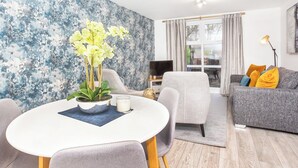 A modern living room with a white dining table, grey sofa, and a blue textured wall. - Minsters Reach Apartment Two - UK2747 (York)