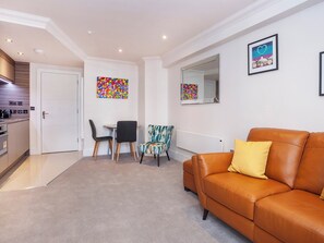 A modern living room with a brown leather sofa, a dining area with two chairs, and a kitchen in the background. - 1 bedroom accommodation in York (York)