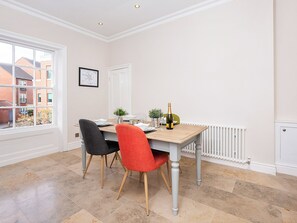 A dining area with a table, chairs, a bottle of champagne, and a window with a view of buildings. - George Street Two - UK2767 (York)