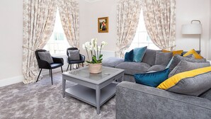 A living room with a grey sofa, two armchairs, a coffee table, and a chandelier. - George Street Two - UK2767 (York)
