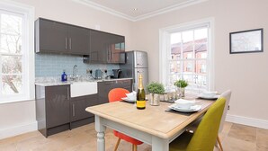 A modern kitchen with dark cabinets, a marble countertop, and a dining area with a wooden table and chairs. - George Street Two - UK2767 (York)