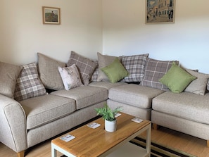 A living room with a sofa set, a coffee table, and two framed pictures on the wall.