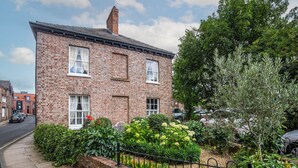 A brick building with a garden in front, a metal fence, and a paved sidewalk. - George Street One - UK2766 (York)