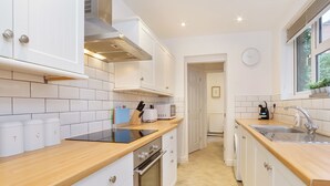 Een moderne keuken met witte kastjes, een houten aanrecht, een ingebouwde oven, een magnetron en een spoelbak.