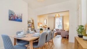 Een eetgedeelte met een houten tafel voor vier personen, omringd door stoelen. Op de achtergrond is een bank en een lamp te zien.