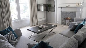 A modern living room with a grey sofa, a coffee table, and a fireplace. - This stunning Victorian property has just finished a full renovation. (Elgin)