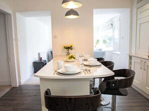 Una cocina moderna con una isla central, muebles blancos y vistas al exterior.