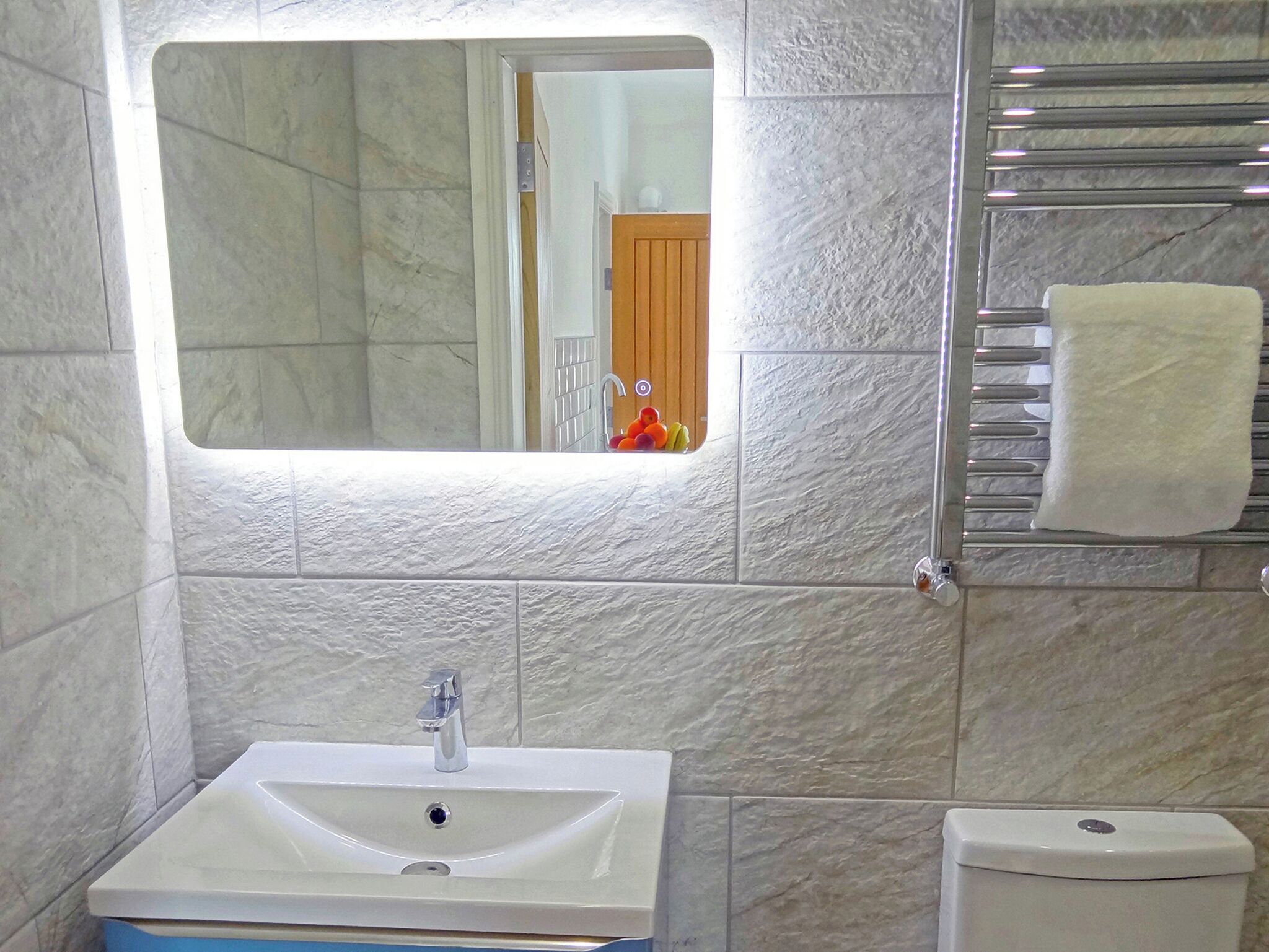 Un baño con un lavamanos blanco, un espejo y un inodoro.