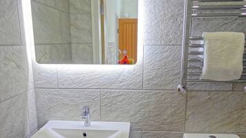 Un baño con un lavamanos blanco, un espejo y un inodoro.